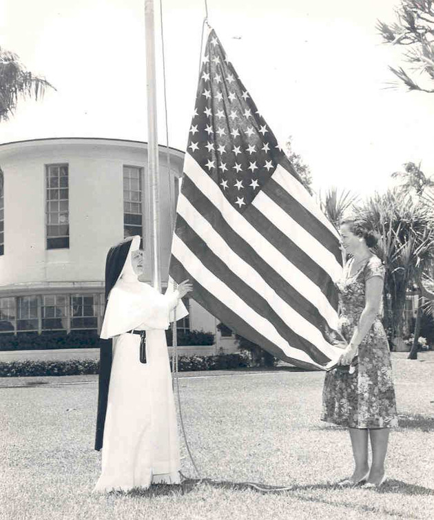 Sister Jerome Kishpaugh and Rosemarie Walfield raise the American flag on campus